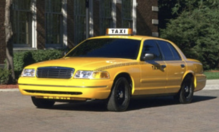 A yellow taxi driving down the street.